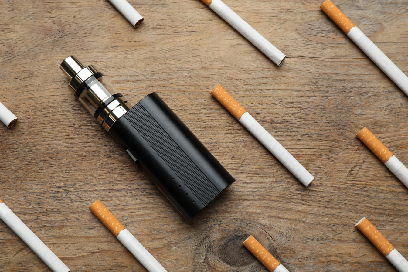Cigarettes and Vaping Device on Wooden Background, Flat Lay. Smo